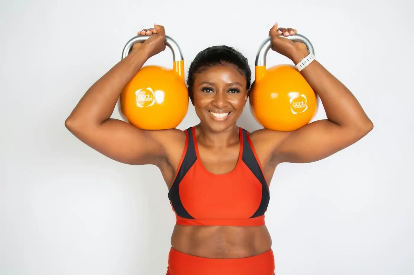 Sportive souriante tenant deux kettlebells